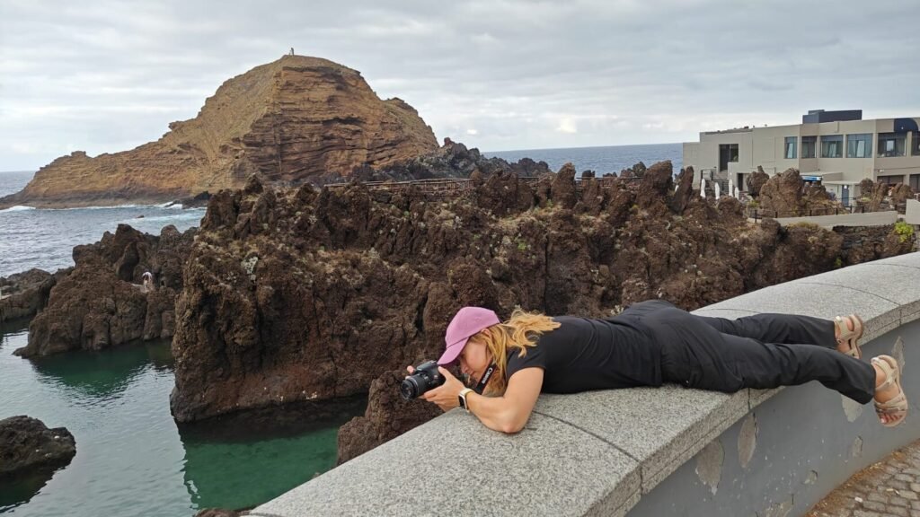 Bea photographing the volcanic coastline in Madeira, camera in hand