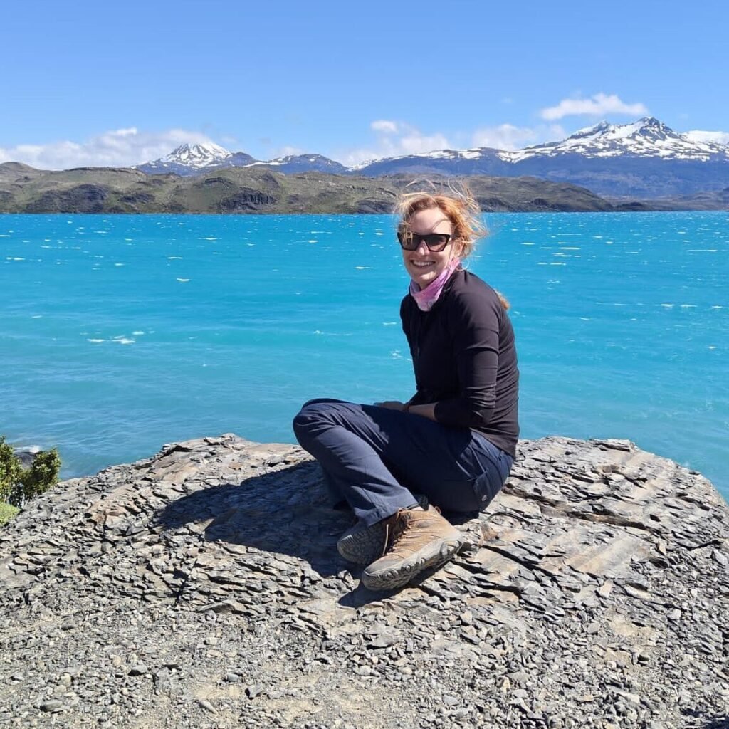 Bea, author of this beginner travel guide, sitting by a mountain lake