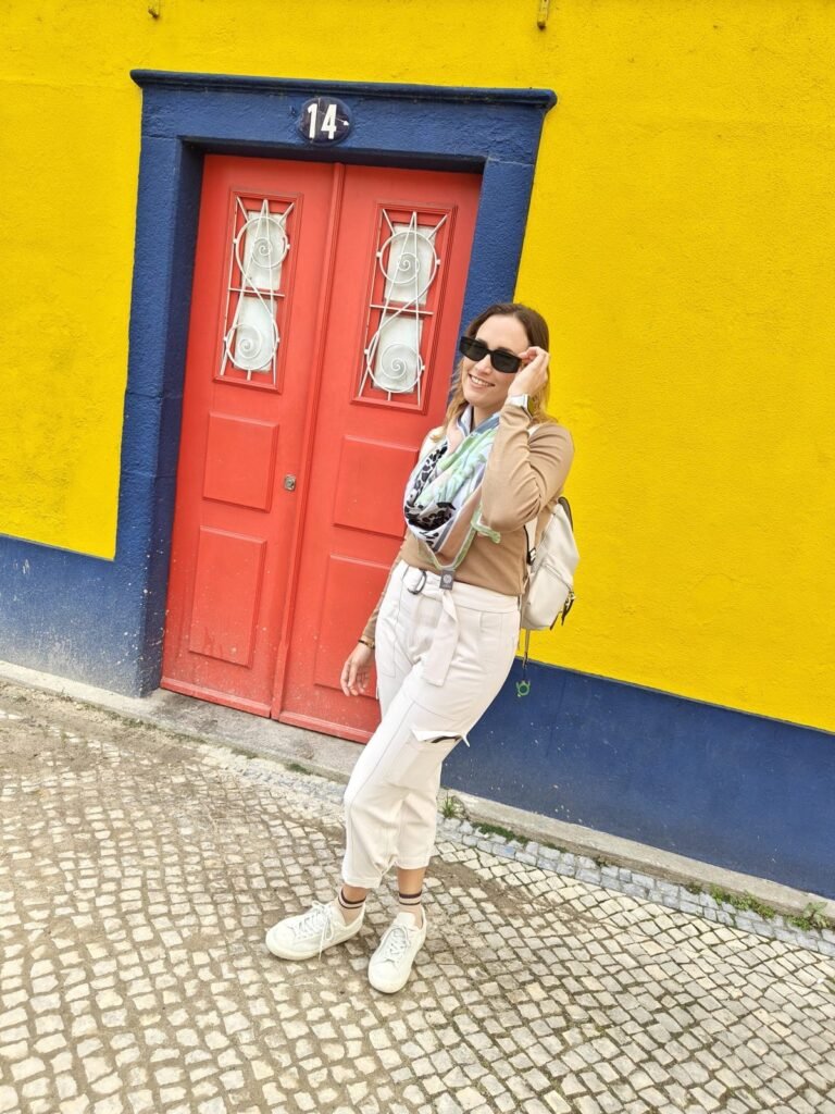 Bea beside a yellow wall and red door in Portugal, September 2024