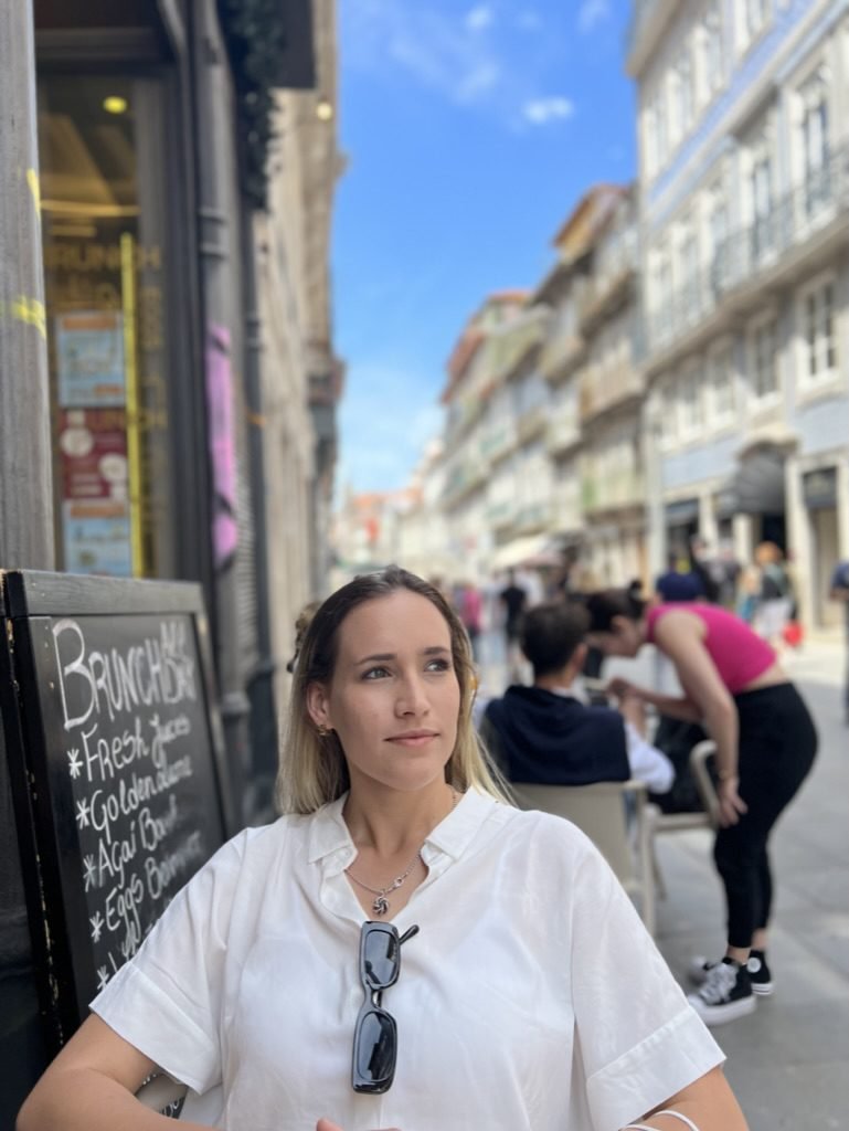Bea con camisa blanca en un café al aire libre en una calle soleada de Europa