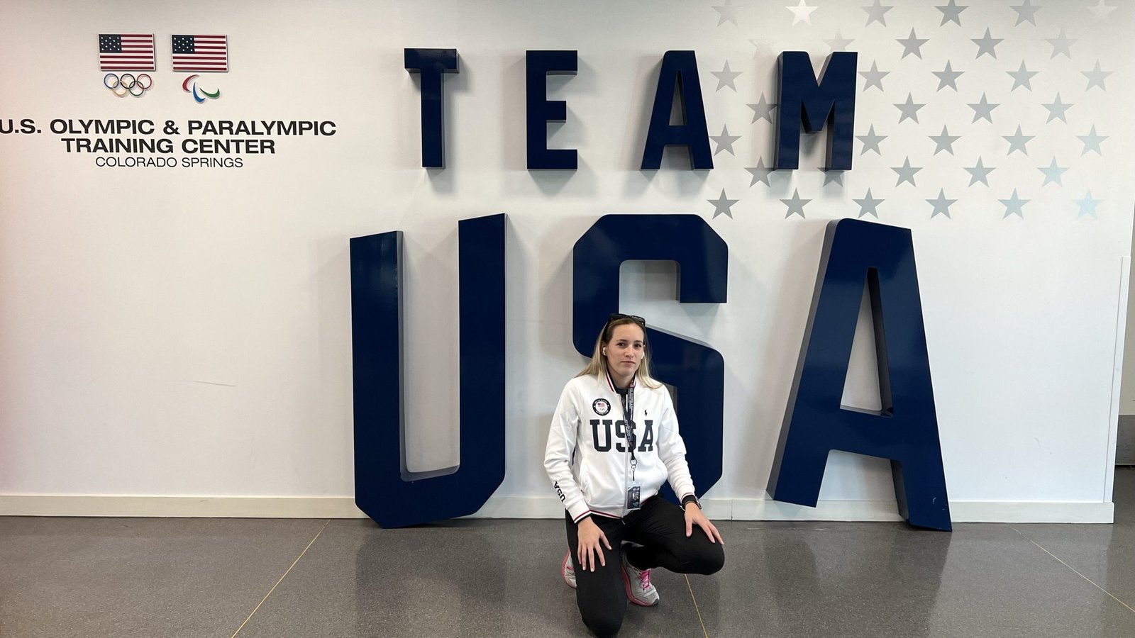 Bea kneeling in front of the Team USA sign at the U.S. Olympic & Paralympic Training Center in Colorado Springs
